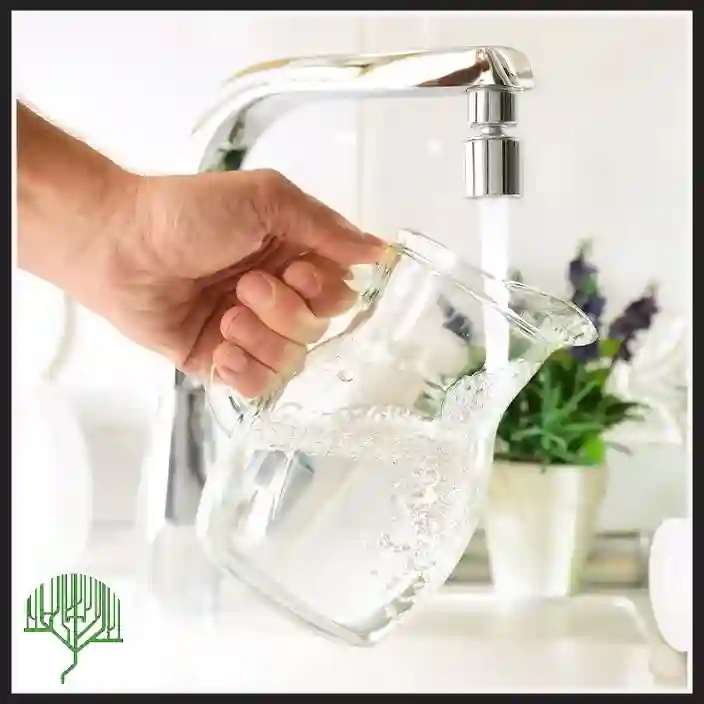 Hand holding a glass of clean water under a running kitchen faucet