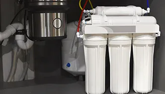 A reverse osmosis water filtration system with three vertical filter cartridges installed under a kitchen sink next to plumbing pipes and a garbage disposal unit.